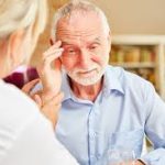 Concerned family member assisting elderly parent with memory tasks in a safe, organized home.