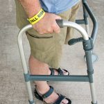 Older adult man using a walker with a fall risk wrist brace, representing mobility challenges and the need for home safety and fall prevention